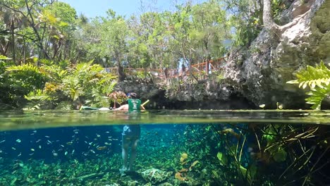 POV-of-people-doing-diving-in-crystal-clear-turquoise-waters-at-Nicte-ha-cenote-in-Tulum,-Mexico