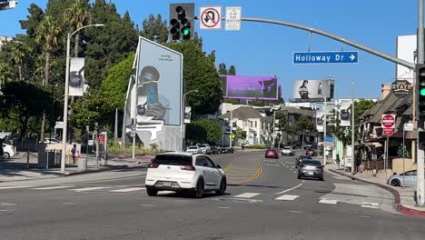 Coches-Que-Pasan-Por-La-Intersección-En-El-Concurrido-Sunset-Boulevard,-Vista-En-Primera-Persona