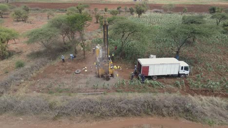 Workers-watch-over-drilling-machine-boring-hole-for-water-well-in-rural-Africa-fields