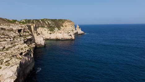 Aerial-view-flying-along-the-steep,-rocky-coastline-of-sunny-Malta-island