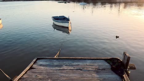 Tilt-Up-Shot-Of-Boat-Anchored-Near-Wooden-Dock-In-River,-Barbate,-Spain