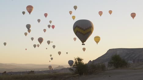 Colourful-hot-air-balloon-drift-over-sunrise-golden-hour-landscape