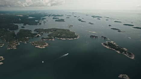 Aerial,-Drone,-Finnish-coast-with-lots-of-islands-and-a-boat-driving-through