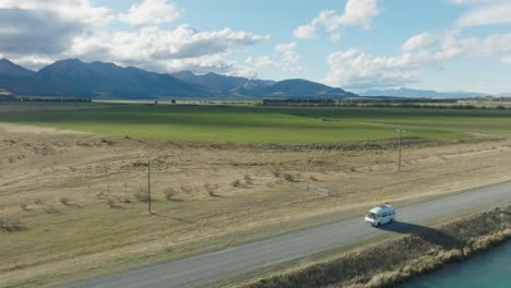 Aerial-landscape-view-of-campervan-road-trip-through-rural-countryside-of-Mackenzie-District-and-Pelennor-Fields-shooting-location-from-Lord-of-the-Rings,-South-Island-in-New-Zealand-Aotearoa