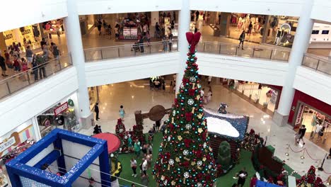 Decorated-Christmas-tree-inside-a-shopping-mall,-people-walking,-taking-pictures,-and-enjoying-the-Christmas-atmosphere