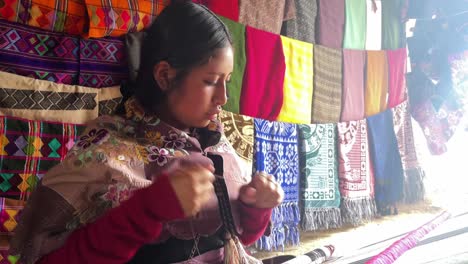 young-Tzotzil-Mayan-woman-weaving-a-textile-in-the-region-of-San-Cristobal-de-las-Casas,-Chiapas-state-while-wearing-traditional-clothing-of-her-culture