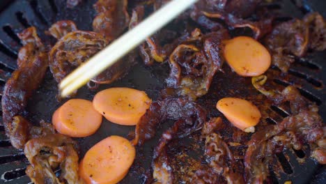 Close-up-shot-of-cooking-Barbeque-meat-and-sausage-on-grill-pan-using-chopsticks