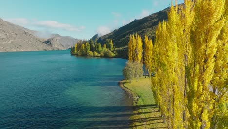 Aerial-view-revealing-tourist-campervan-camped-at-idyllic-scenic-location-overlooking-pristine-lake-with-turquoise-water-in-South-Island-of-New-Zealand-Aotearoa