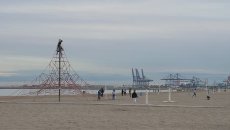 Niños-Jugando-En-La-Playa-Y-Escalando-Cuerda-Neta-Vista-A-La-Costa-Con-Grúas-Valencia