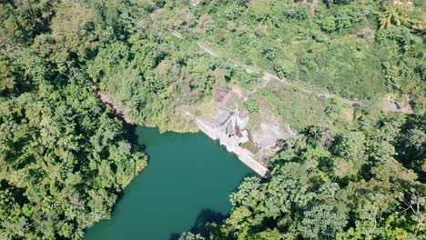 Aerial-top-down-shot-Tireo-Dam-surrounded-by-green-landscape-in-summer---Bonao,-Dominican-Republic