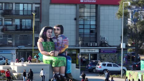 Families-and-people-walking,-taking-photos,-and-enjoying-the-sunny-day-around-the-sculpture-‘Sentados-frente-al-mar’-in-Puerto-Montt,-Chile