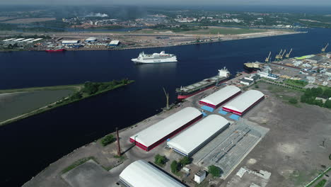 Aerial-clip-of-a-coastal-dockyard-with-storage-warehouses-and-moving-yacht-in-the-water-channel