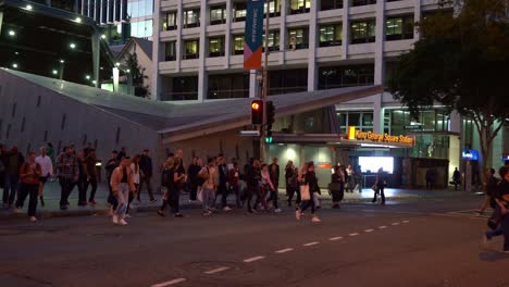 Large-crowds-of-commuters-crossing-the-road-on-Albert-and-Adelaide-street-in-Brisbane-city-in-the-evening-with-King-George-Square-busway-station,-bus-interchange-in-the-background