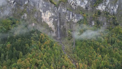 Panoramaaufnahme-Von-Links-Nach-Rechts-Eines-Nebligen-Berges-Mit-Einem-Dünnen-Wasserfall,-Der-Den-Hügel-Hinunterfließt