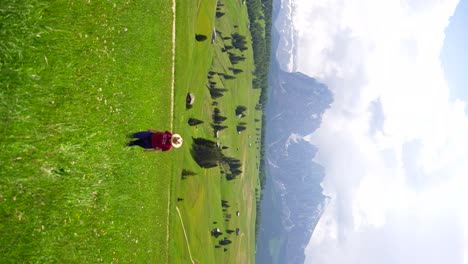 Mujer-Con-Sombrero-Disfrutando-Del-Paisaje-Montañoso-De-Alpe-Di-Siusi-En-Medio-De-Una-Exuberante-Pradera