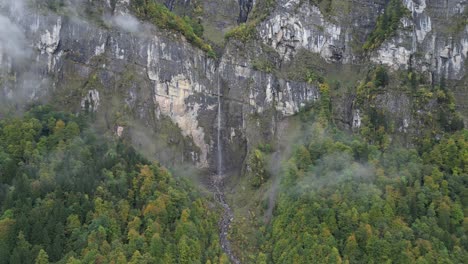 Vista-Aérea-De-Una-Cascada-Con-Un-Fino-Arroyo-Que-Fluye-Desde-Una-Alta-Cumbre-De-Montaña-En-Klöntalersee-Glarus,-Suiza