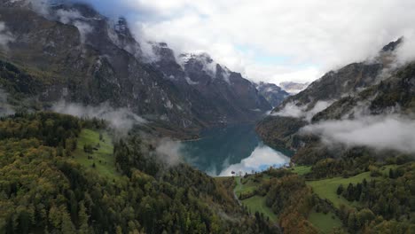 Panoramic-aerial-shot-of-high-mountains-and-lake-situated-in-the-valley-Klöntalersee-Glarus-Switzerland