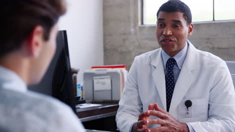 Concerned-mixed-race-male-doctor-speaking-to-patient