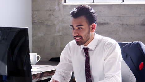 Young-Hispanic-man-working-in-office,-smiles-to-camera