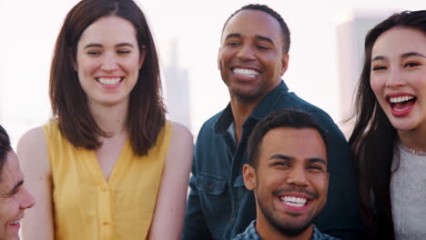 Portrait-Of-Friends-Gathered-On-Rooftop-Terrace-For-Party-With-City-Skyline-In-Background