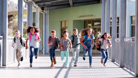 Elementary-school-kids-running-to-camera-in-school-corridor