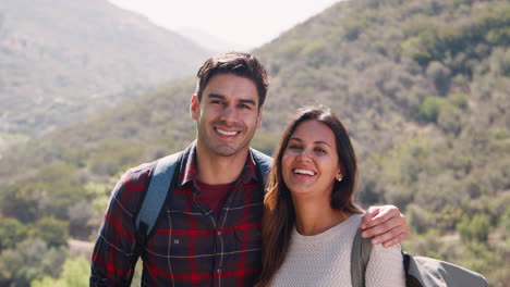 Young-smiling-couple-embracing-during-a-summer-mountain-hike