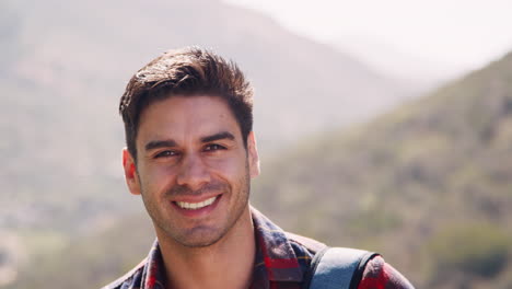 Young-man-on-a-mountain-hike-smiling-to-camera,-close-up
