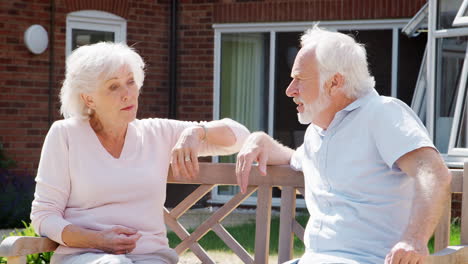 Retired-Couple-Sitting-On-Bench-And-Talking-In-Assisted-Living-Facility