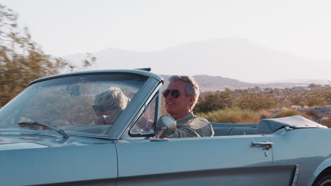 Senior-white-couple-driving-classic-convertible-on-highway