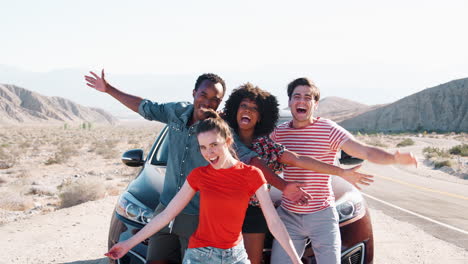Young-adult-friends-on-road-trip-have-fun-posing-by-the-car