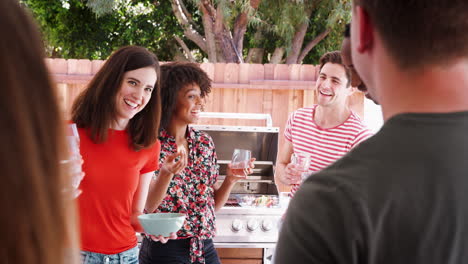 Young-adult-friends-standing-with-drinks-at-a-backyard-party