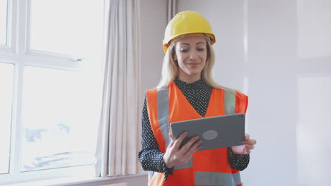 Female-Surveyor-In-Hard-Hat-And-High-Visibility-Jacket-With-Digital-Tablet-Carrying-Out-House-Inspection