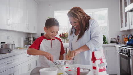 Pre-teen-Hispanic-boy-and-his-grandmother-making-cakes-in-the-kitchen,-mixing-cake-mix,-close-up