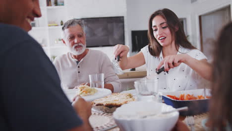 Close-up-of-Hispanic-family-sitting-at-the-table-serving-food-at-a-family-meal,-selective-focus