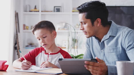 Pre-teen-Hispanic-boy-sitting-at-the-dining-table-working-with-his-home-tutor,-close-up