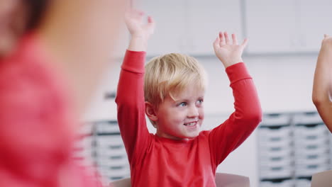 Infant-schoolchildren-waving-their-arms-in-the-air-and-clapping-during-a-lesson,-close-up