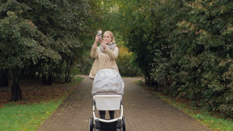 A-woman-with-a-baby-carriage-in-a-park-taking-pictures