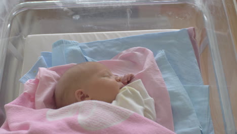 Newborn-baby-girl-in-crib-being-wheeled-down-a-corridor
