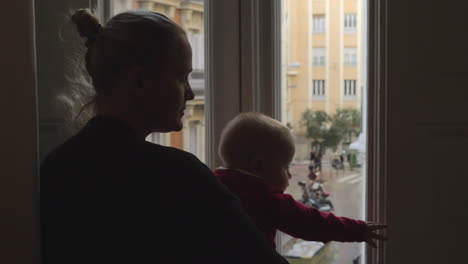 Adorable-baby-girl-looking-out-the-window-with-her-mother