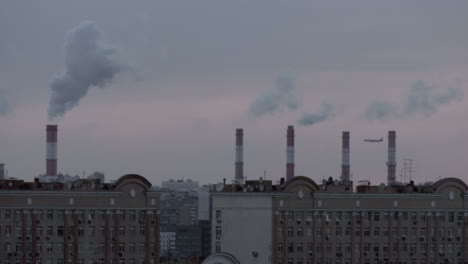 Smoking-chimneys-city-rooftops-and-a-flying-airplane