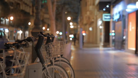 Walking-by-bike-sharing-station-in-night-city-Valencia
