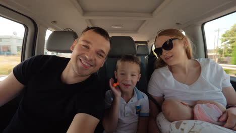 Happy-family-of-four-traveling-by-car