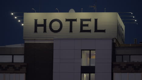 Un-Cartel-De-Hotel-En-Lo-Alto-De-Un-Edificio-Contra-El-Oscuro-Cielo-Nocturno
