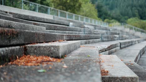 Athletic-man-training-on-the-steps-of-an-empty-grandstand-at-the-edge-of-a-running-track,-close-up