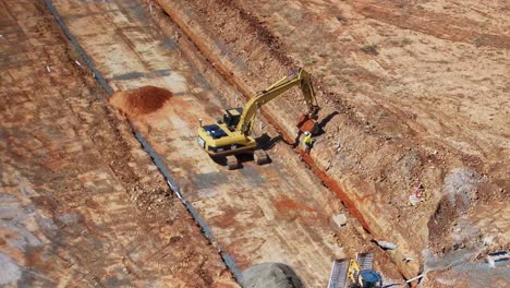 Yarrawonga,-Victoria,-Australia---22-November-2023:-Worker-directing-track-loader-operator-tipping-soil-in-a-trench-on-a-building-site-at-Silverwoods-Estate-in-Yarrawonga