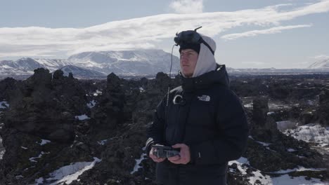 Man-fly-FPV-drone-using-goggles-around-scenic-black-volcanic-landscape