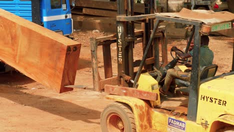 skilled-black-male-labor-loading-a-wooden-trunk-in-sawmill-factory-on-a-truck-using-an-electric-forklift