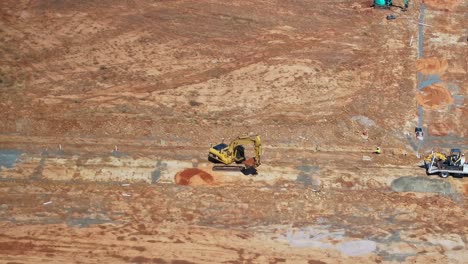 Yarrawonga,-Victoria,-Australia---22-November-2023:-Track-loader-operator-scoops-up-a-pile-of-soil-and-is-then-directed-by-another-worker-to-dump-the-load-into-a-trench