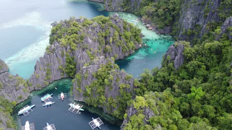 Clear-blue-water-of-twin-lagoon-amid-towering-karst-and-lush-tropical-foliage,-Coron