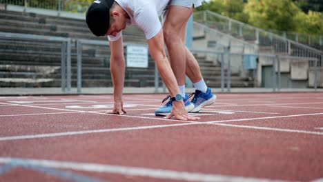 Corredor-Masculino-Deportivo-Se-Prepara-Para-Su-Entrenamiento-En-La-Posición-Inicial-De-La-Pista-De-Atletismo,-Fitness,-Atleta-De-Línea-Preparándose-Para-El-Desafío